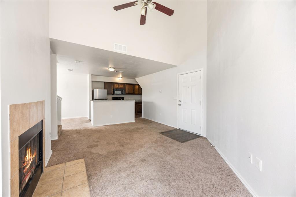 9837 Walnut Street, Unit S203 Dallas, TX 75243 - Photo 5 of 26 Living area featuring a fireplace with a tiled surround, vaulted ceilings, and a ceiling fan