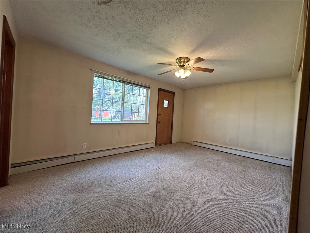 2829 Shellhart Road Barberton, OH 44203 - Photo 13 of 29 Lower level unfurnished bedroom on bottom level, with a baseboard radiator, carpet floors, a ceiling fan, and a textured ceiling