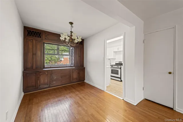 an empty room with wooden floor chandelier and windows