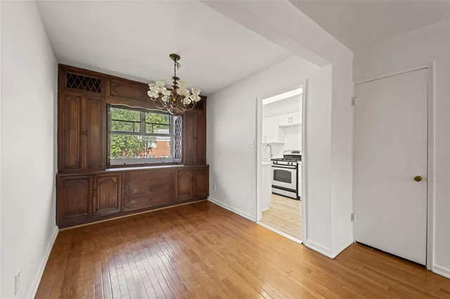 an empty room with wooden floor chandelier and windows