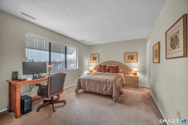 a bedroom with a bed a desk and chair with window