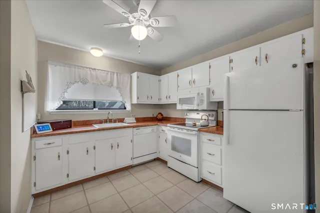 a kitchen with granite countertop white cabinets and white appliances