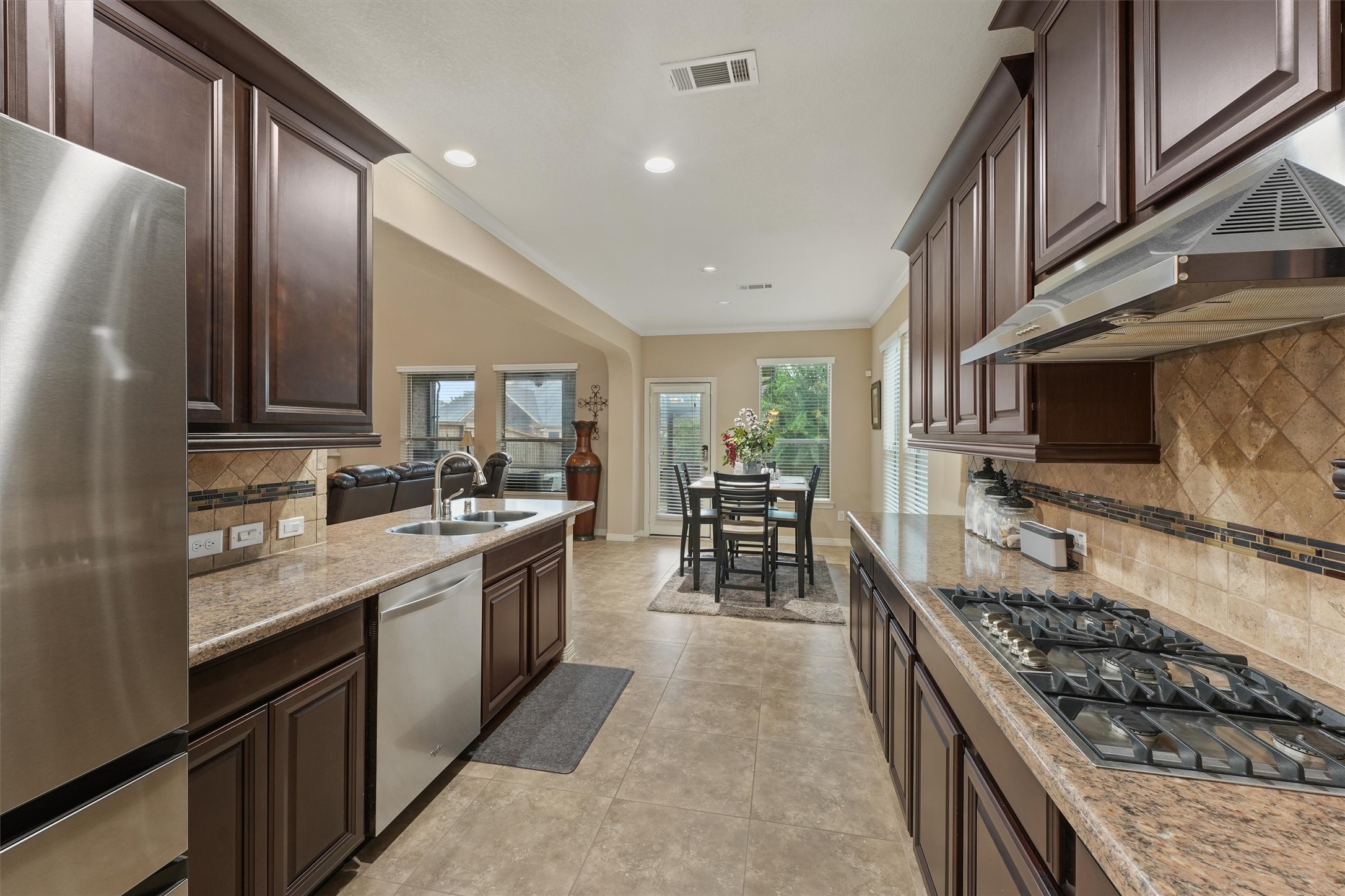 529 Water Street Webster, TX 77598 - Photo 8 of 38 a large kitchen with stainless steel appliances granite countertop a stove top oven a sink a dining table and chairs