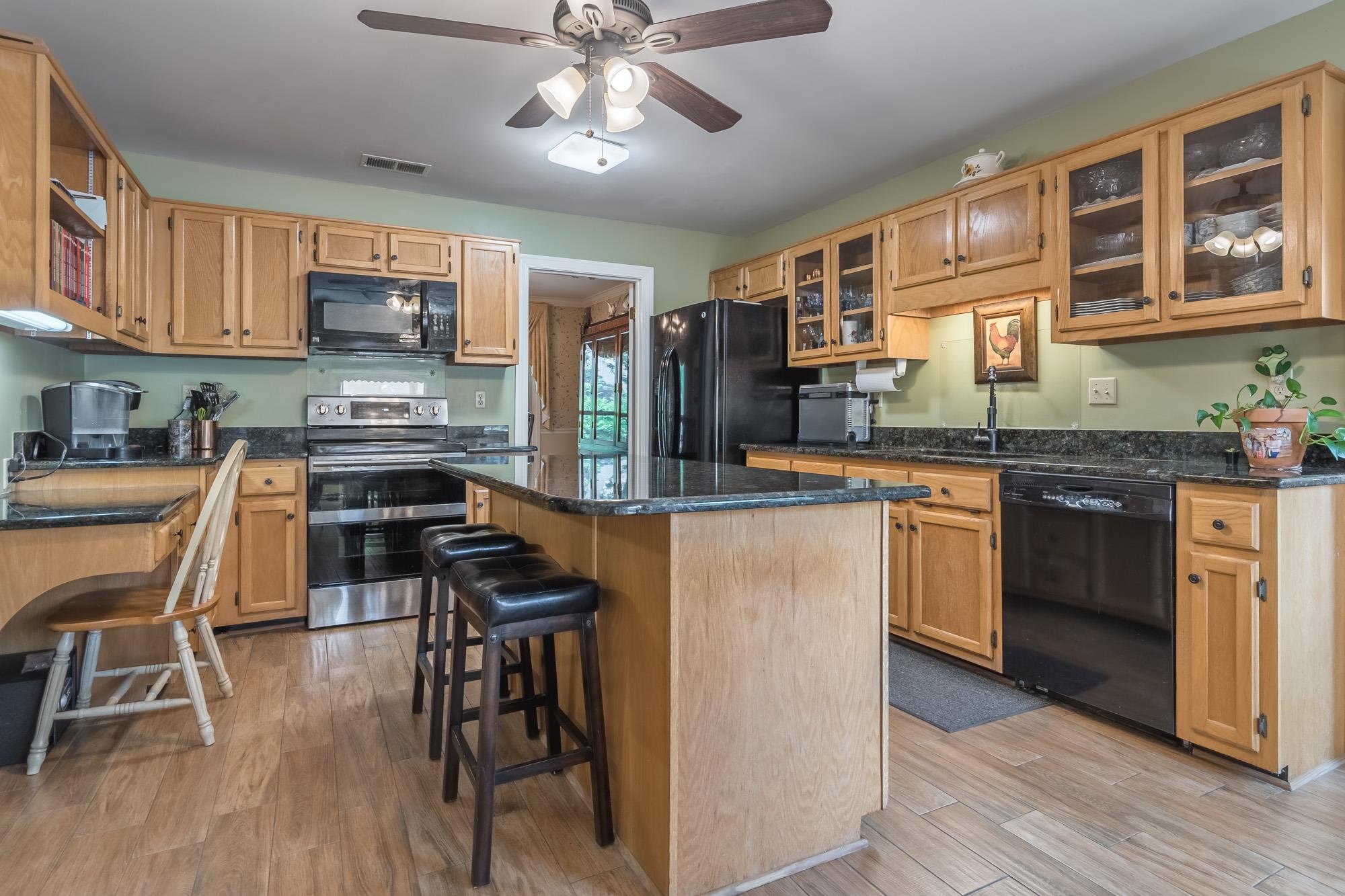 132 South Walnut Bend Road Memphis, TN 38018 - Photo 8 of 23 a kitchen with stainless steel appliances granite countertop a stove top oven a sink dishwasher a dining table and chairs with wooden floor