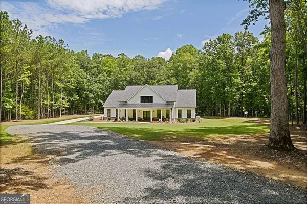 a front view of a house with a yard and large trees