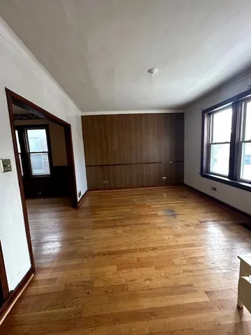 a view of empty room with wooden floor and fan