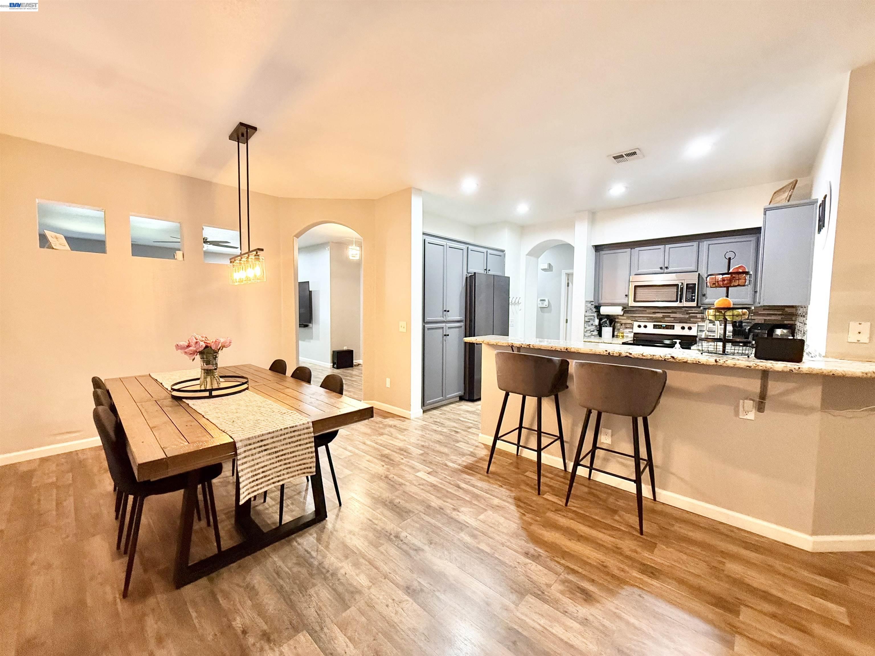 2408 Mountain Pride Court Modesto, CA 95355 - Photo 7 of 25 a kitchen with stainless steel appliances kitchen island granite countertop a table chairs and white cabinets