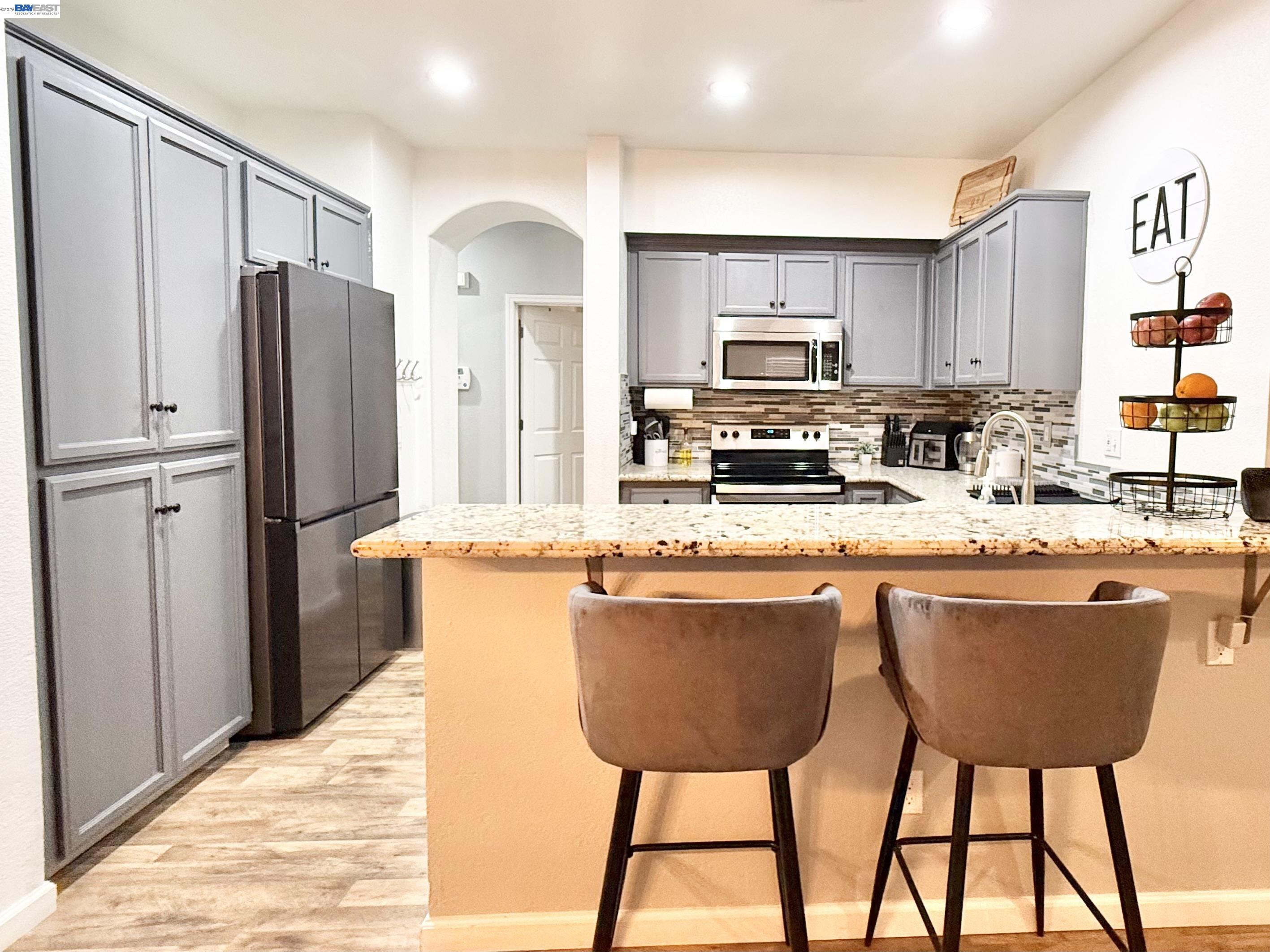 2408 Mountain Pride Court Modesto, CA 95355 - Photo 8 of 25 a kitchen with stainless steel appliances granite countertop a refrigerator a stove a sink dishwasher and a chair with wooden floor