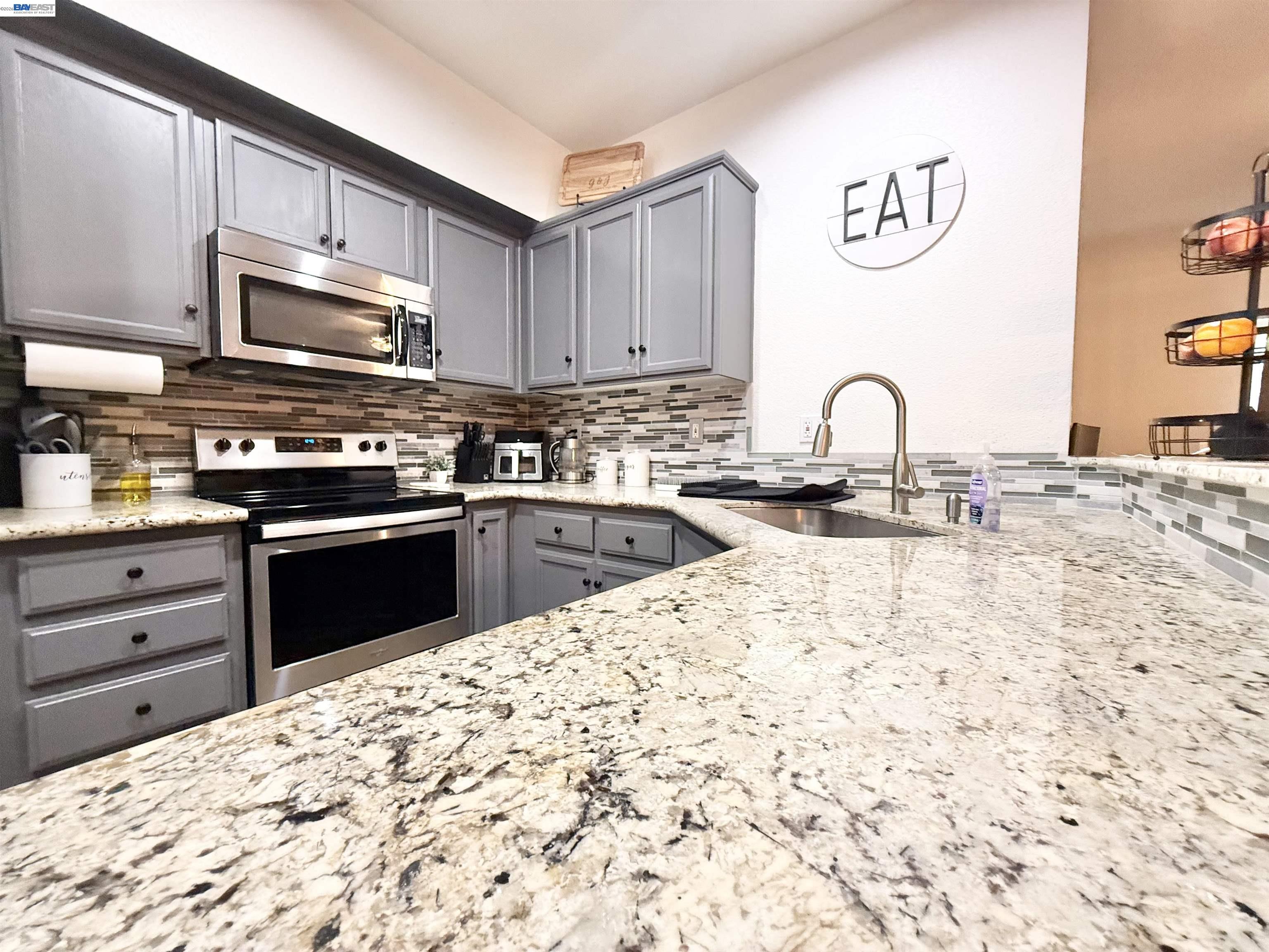 2408 Mountain Pride Court Modesto, CA 95355 - Photo 9 of 25 a kitchen with kitchen island granite countertop a stove top oven microwave and cabinets