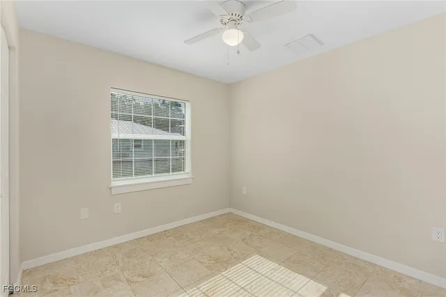 an empty room with windows and ceiling fan