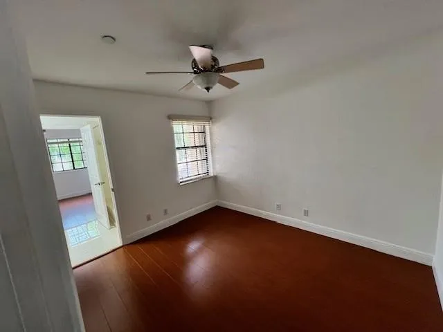 an empty room with wooden floor fan and windows