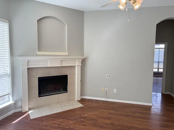 a view of an empty room with wooden floor and a fireplace