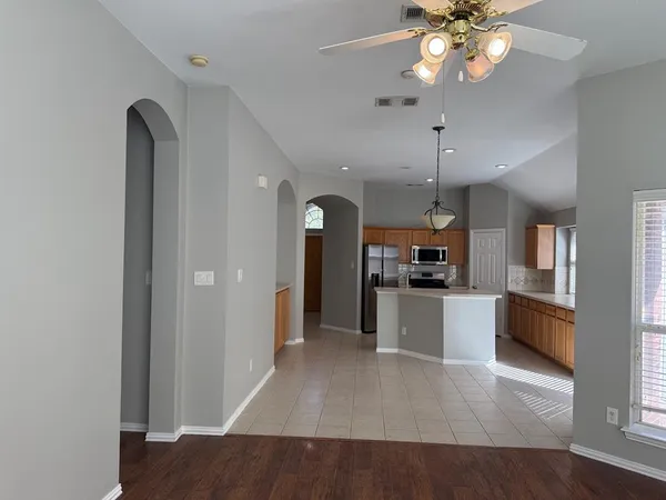 a view of a kitchen with a refrigerator a ceiling fan and wooden floor