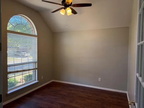 an empty room with wooden floor fan and windows