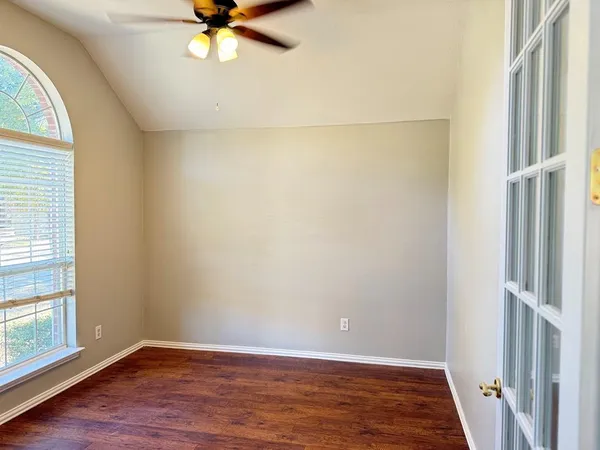 an empty room with wooden floor and fan