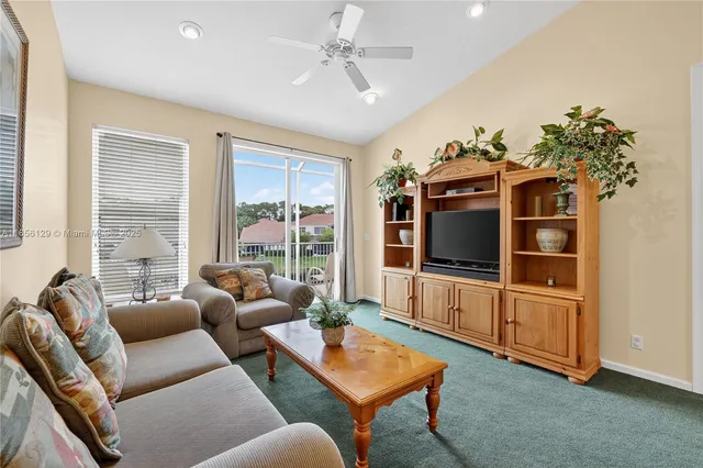 a living room with furniture a flat screen tv and a floor to ceiling window
