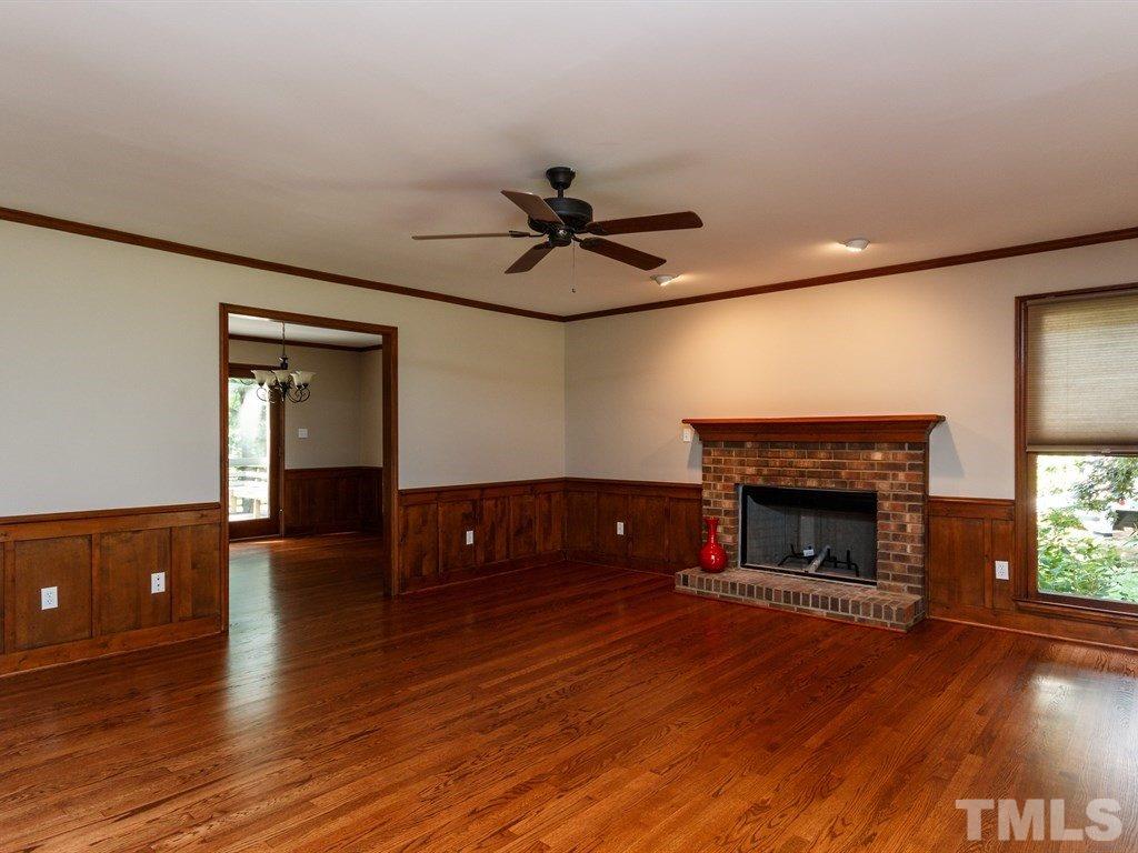 8501 Council Court Raleigh, NC 27615 - Photo 7 of 19 an empty room with wooden floor a fireplace and windows