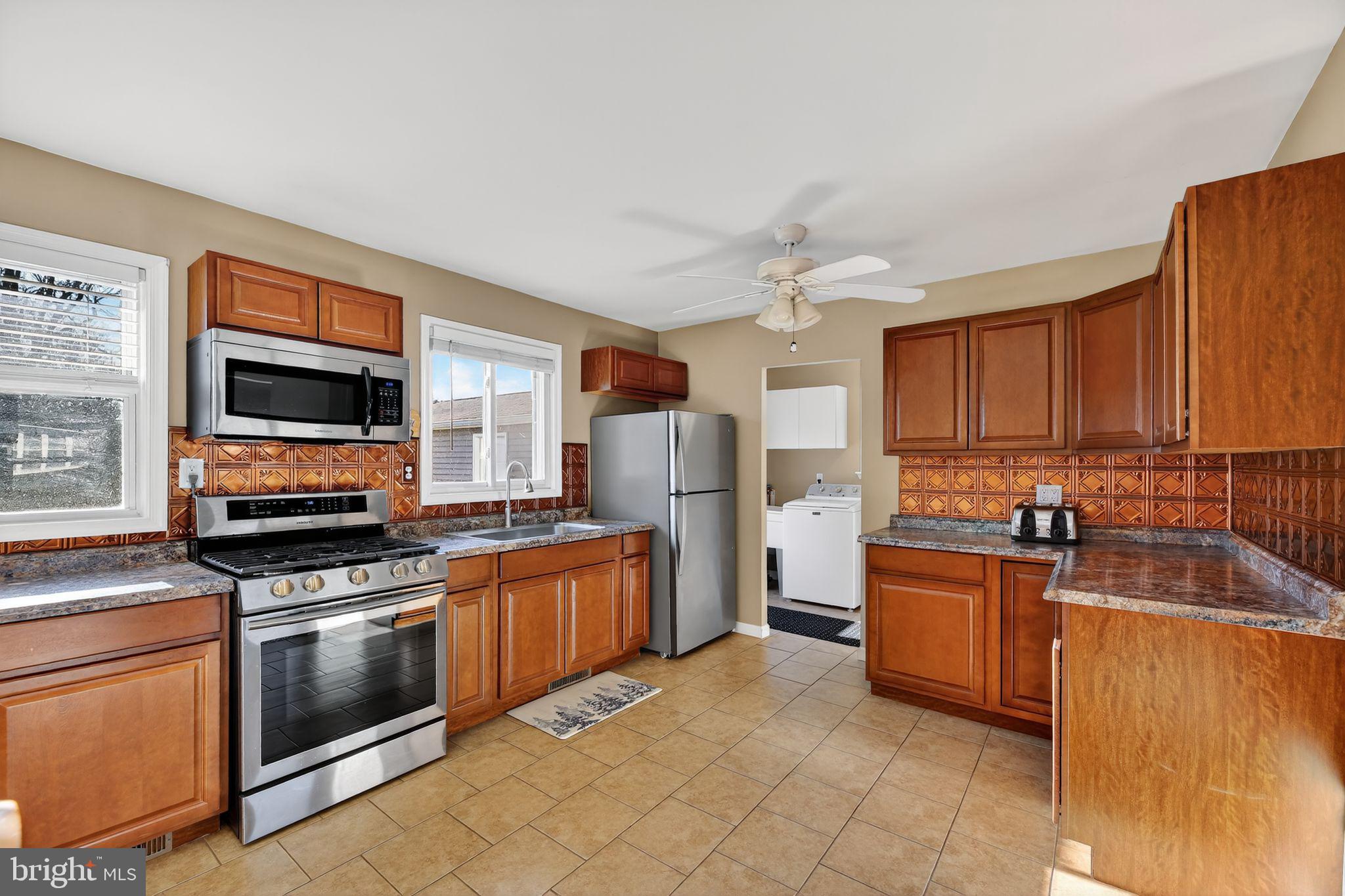 15 Winslow Road Sewell, NJ 08080 - Photo 4 of 18 a kitchen with stainless steel appliances granite countertop a stove top oven a sink dishwasher and a refrigerator with wooden cabinets