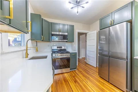 a kitchen with stainless steel appliances granite countertop a refrigerator a stove and a sink
