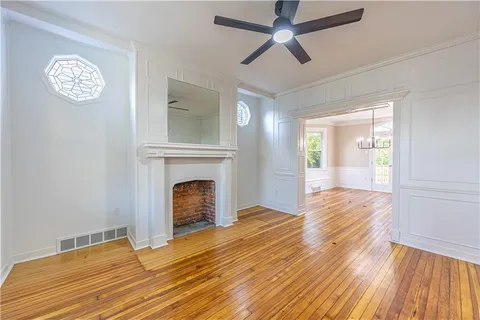 a view of an empty room with wooden floor fireplace and a window