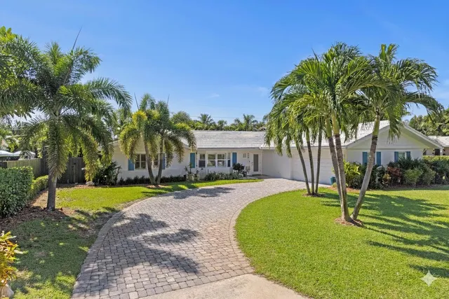 a view of a house with a yard and palm trees