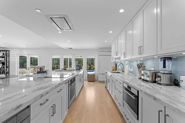 a large kitchen with stainless steel appliances granite countertop a lot of counter space and wooden floors