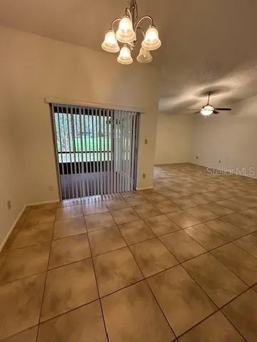 a view of an empty room with a chandelier fan