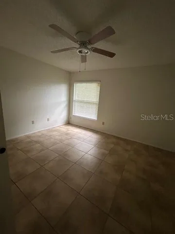an empty room with windows and fan
