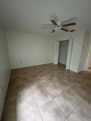 an empty room with a ceiling fan and carpet