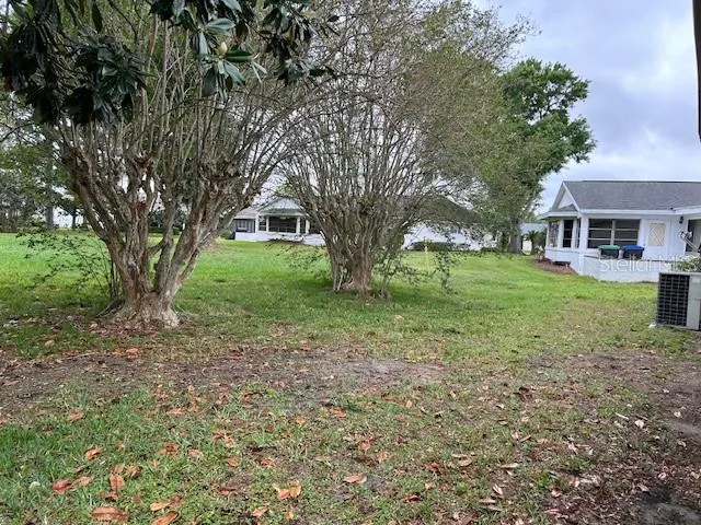 a view of house in front of a big yard with large trees