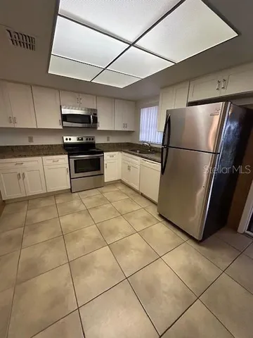 a kitchen with granite countertop a refrigerator and a stove top oven