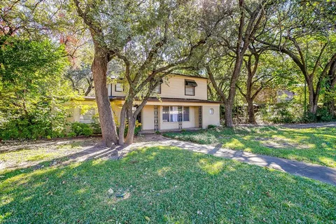 a view of a yard in front of a house with large tree
