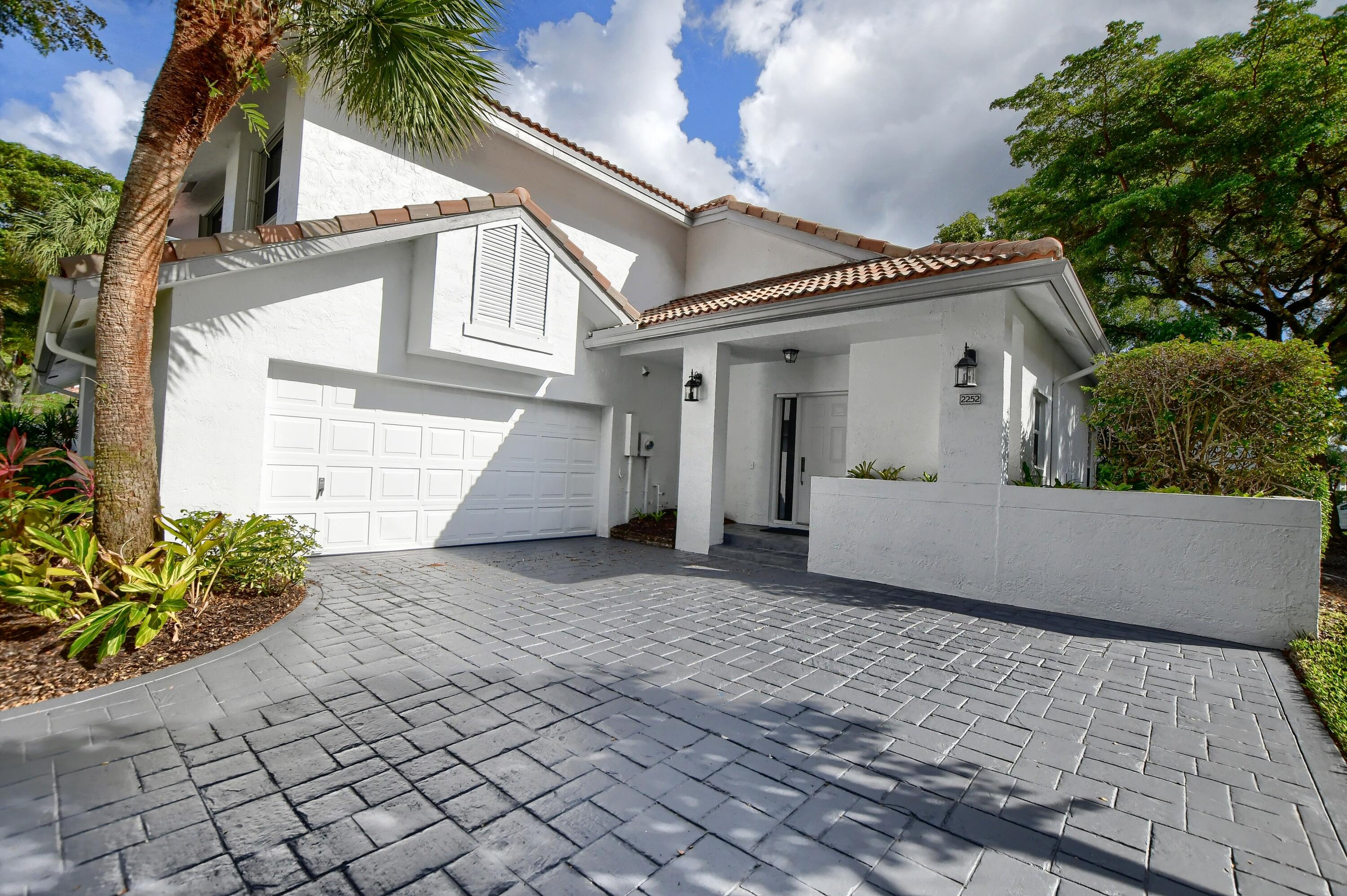 2252 Northwest 53rd Street Boca Raton, FL 33496 - Photo 2 of 41 a view of a white house with a small yard and a large tree