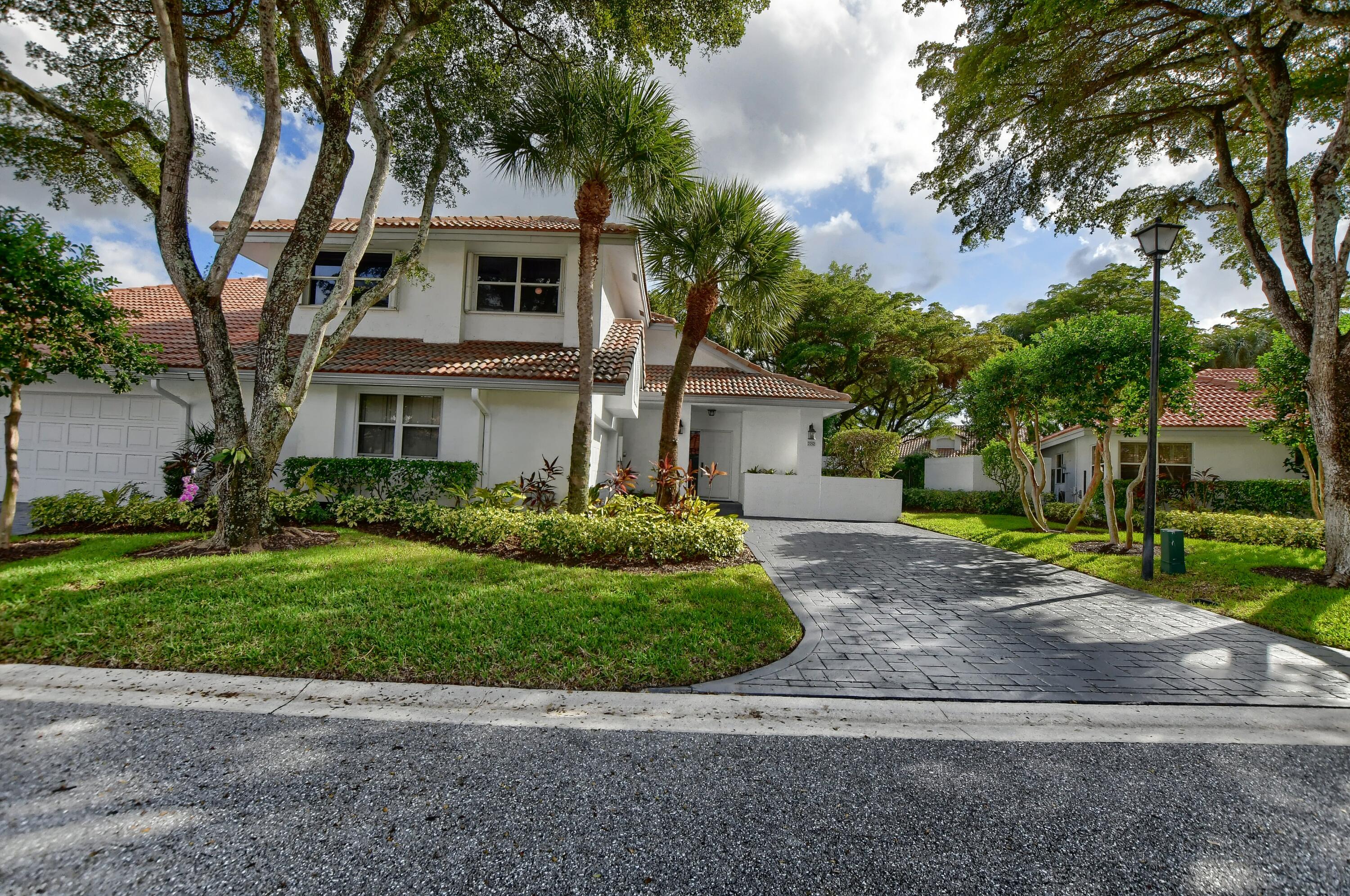 2252 Northwest 53rd Street Boca Raton, FL 33496 - Photo 4 of 41 a front view of a house with a garden and trees