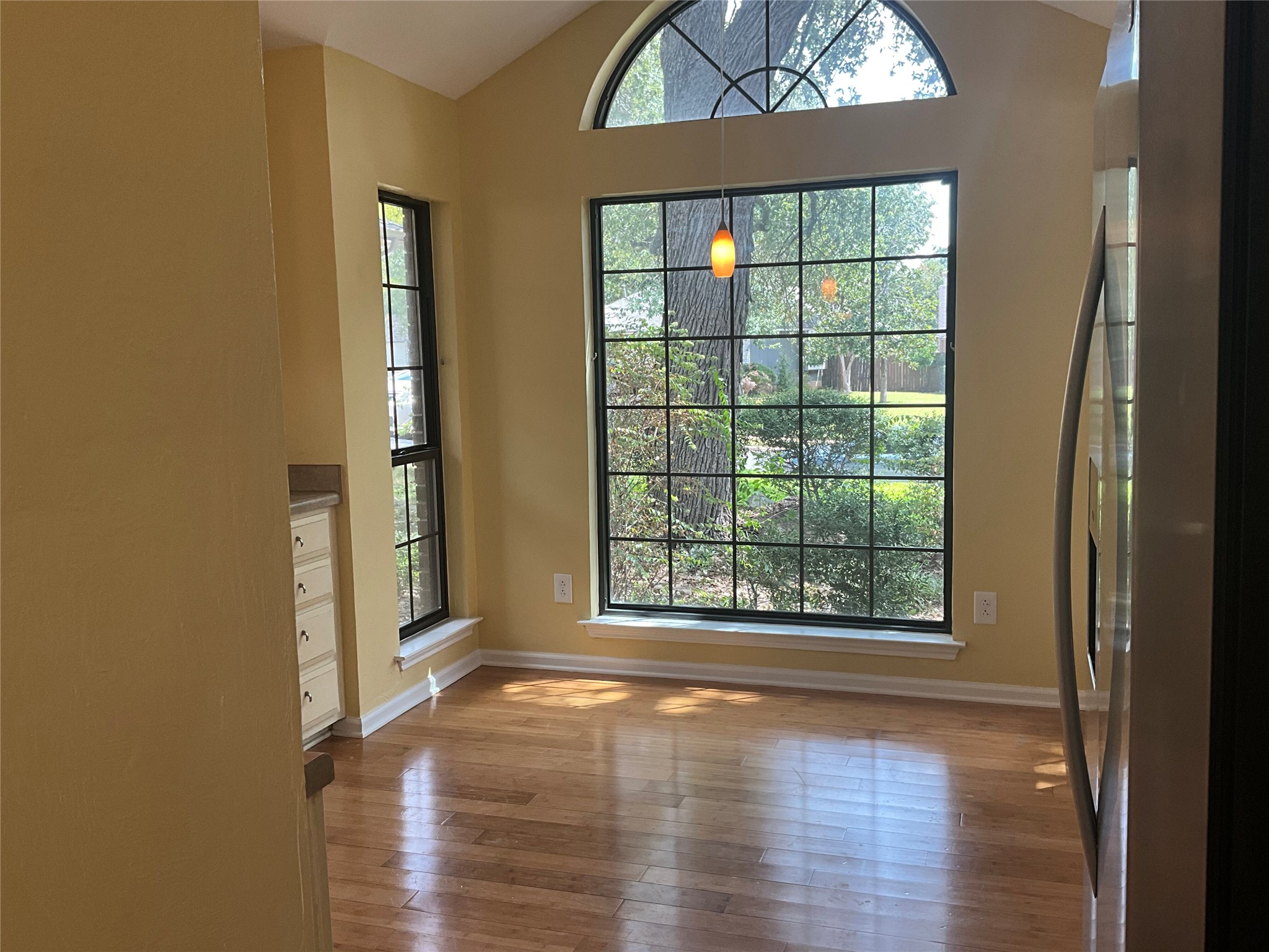 15702 Racine Cove Austin, TX 78717 - Photo 9 of 27 A sun-drenched dining area features soaring vaulted ceilings and elegant hardwood flooring.