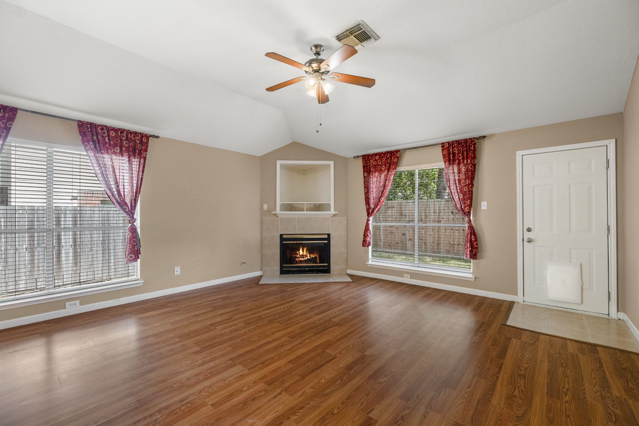 9109 Benwick Street Spring, TX 77379 - Photo 12 of 28 an empty room with windows fireplace and a ceiling fan