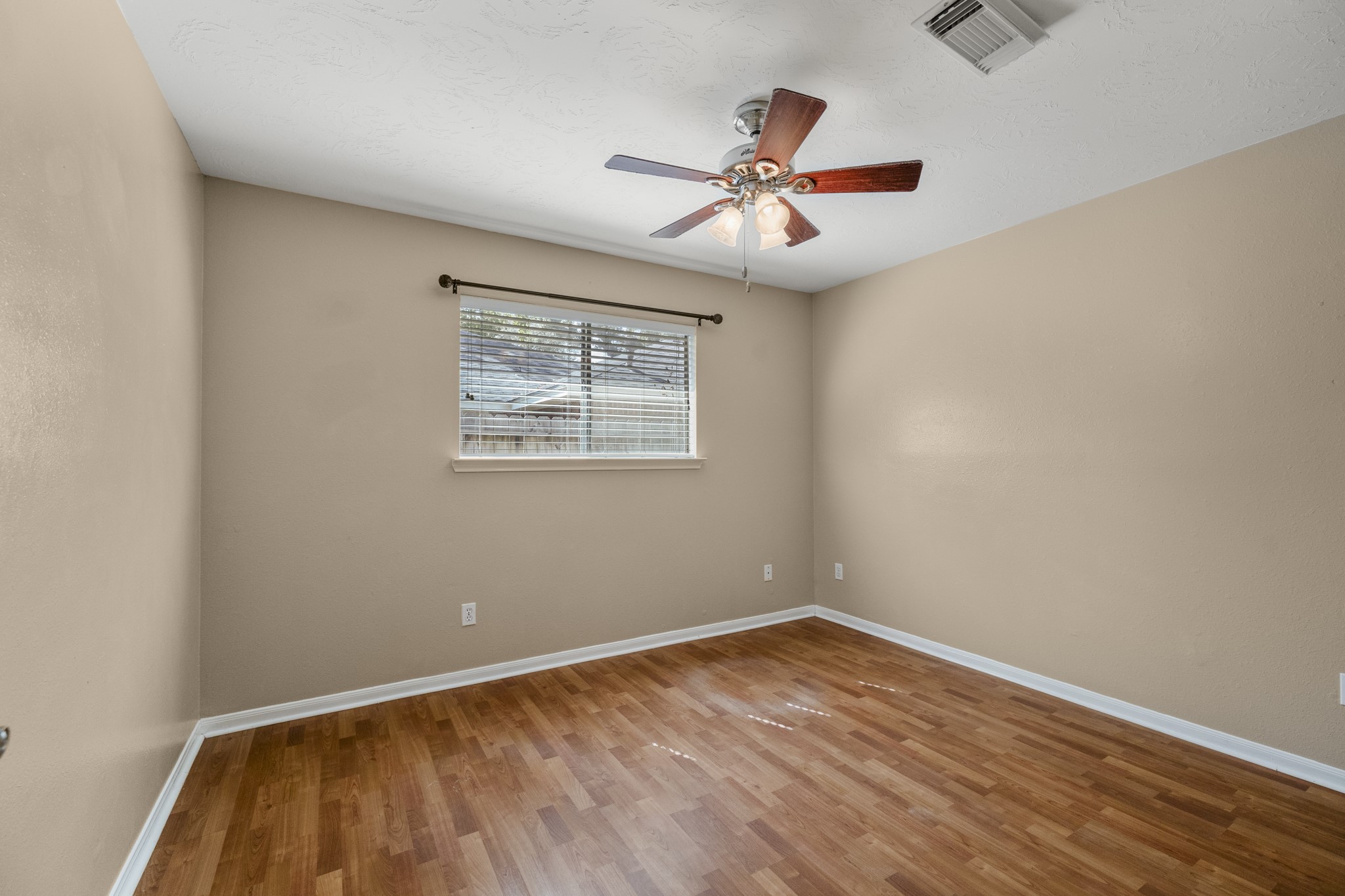 9109 Benwick Street Spring, TX 77379 - Photo 20 of 28 a view of an empty room with wooden floor and a ceiling fan