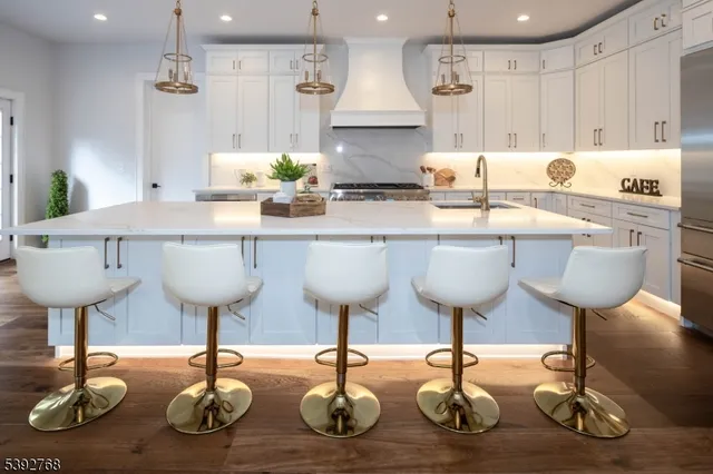 a kitchen with granite countertop a stove a sink dishwasher and white cabinets with wooden floor