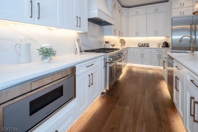 a living room with couches and kitchen view with wooden floor