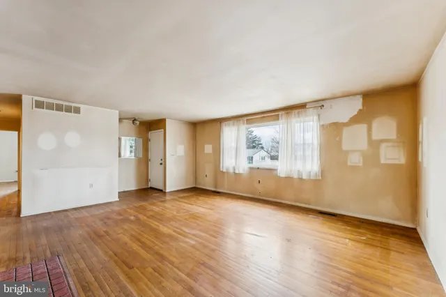 an empty room with wooden floor fireplace and windows