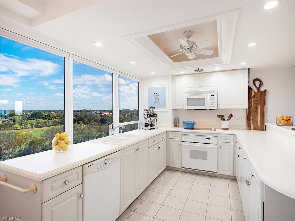 6825 Grenadier Boulevard, Unit 604 Naples, FL 34108 - Photo 5 of 12 a kitchen with a sink a stove and white cabinets
