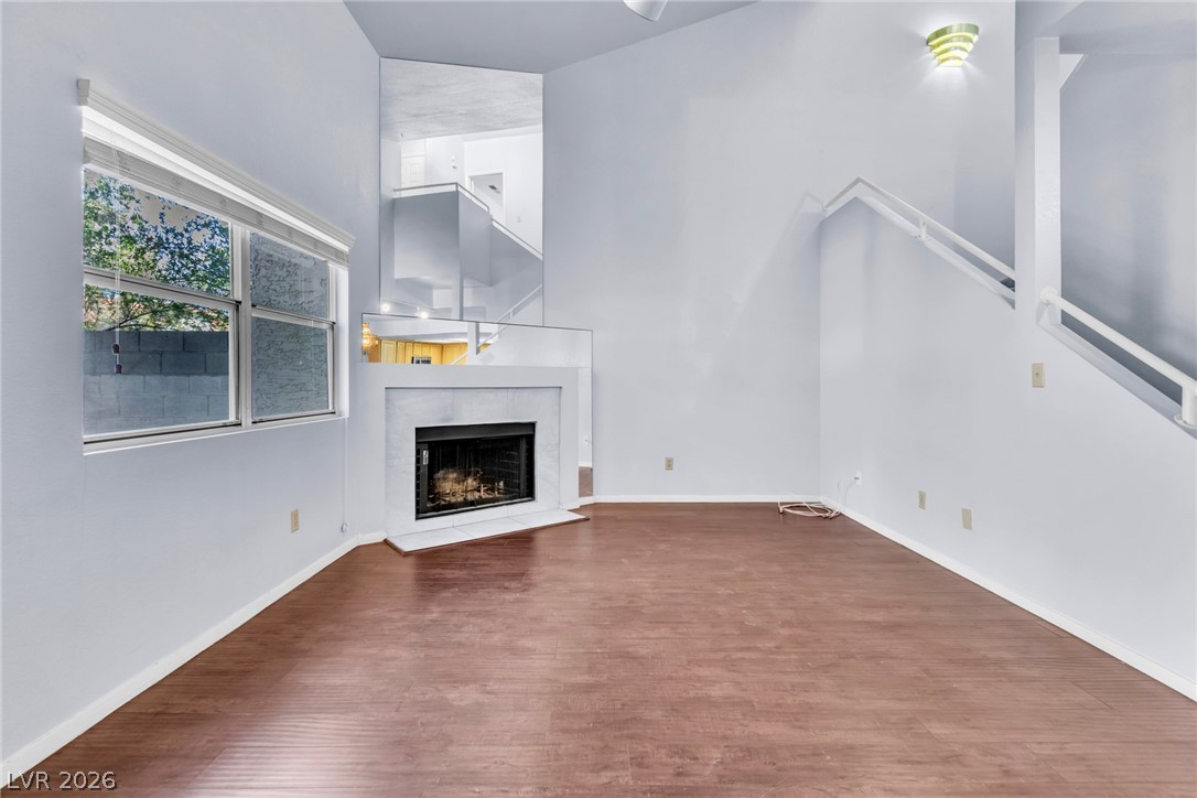 6250 West Flamingo Road, Unit 98 Las Vegas, NV 89103 - Photo 14 of 40 Unfurnished living room featuring baseboards, a high ceiling, a high end fireplace, and wood finished floors
