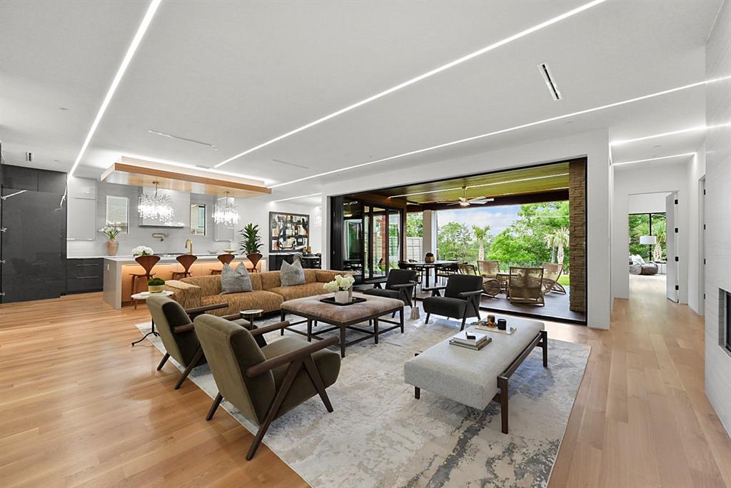 9457 Waterview Road Dallas, TX 75218 - Photo 7 of 25 Spacious living area featuring light wood-finish flooring, linear ceiling lighting, and a large multi-panel sliding glass door leading to an outdoor covered patio