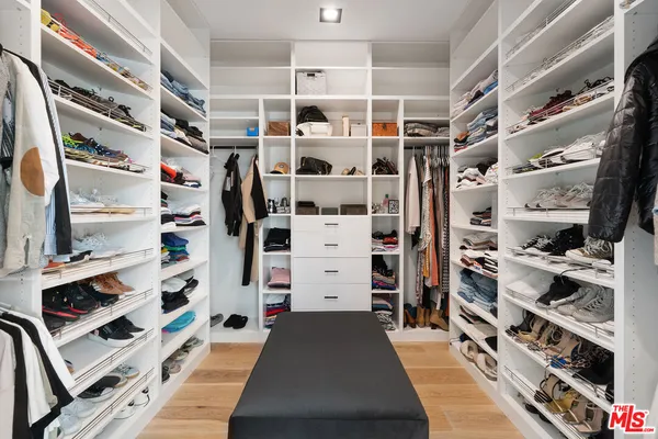 a view of walk in closet with clothes and shoes