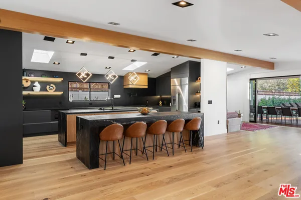 a view of dining room kitchen with stainless steel appliances granite countertop a stove and a wooden floor
