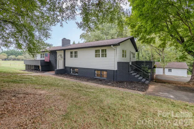 a view of a house with a yard and a large tree
