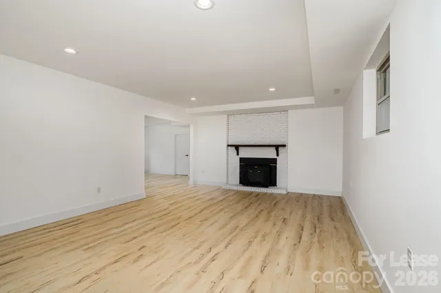 a view of empty room with wooden floor and fireplace