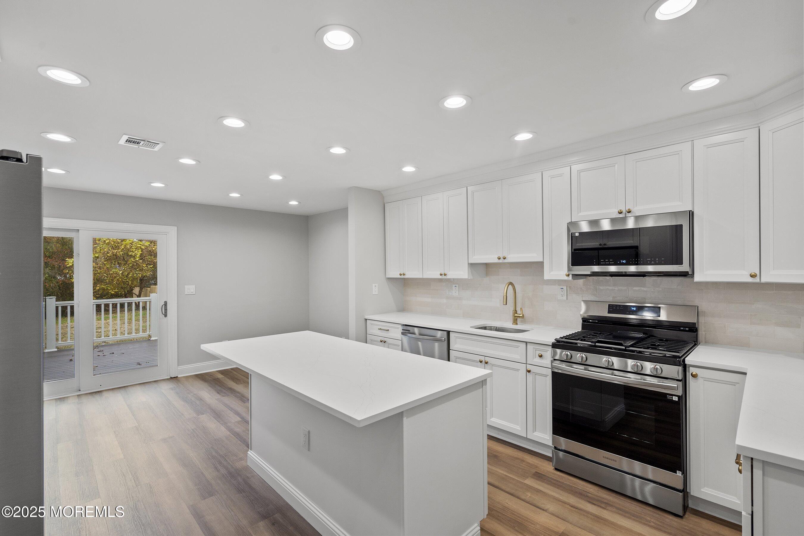 122 West 6th Street Howell, NJ 07731 - Photo 3 of 16 a kitchen with a stove a sink and a microwave