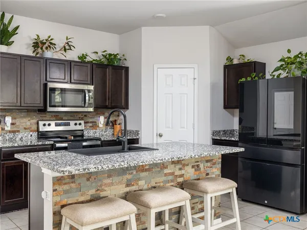 a kitchen with stainless steel appliances granite countertop a stove top oven microwave and refrigerator