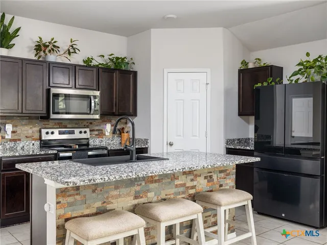 a kitchen with stainless steel appliances granite countertop a stove top oven microwave and refrigerator